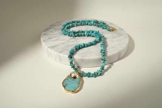 Turquoise beaded necklace with a pendant on a white marble surface