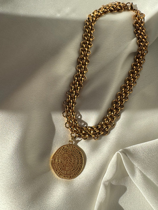 Gold chain necklace with a pendant on a light fabric background