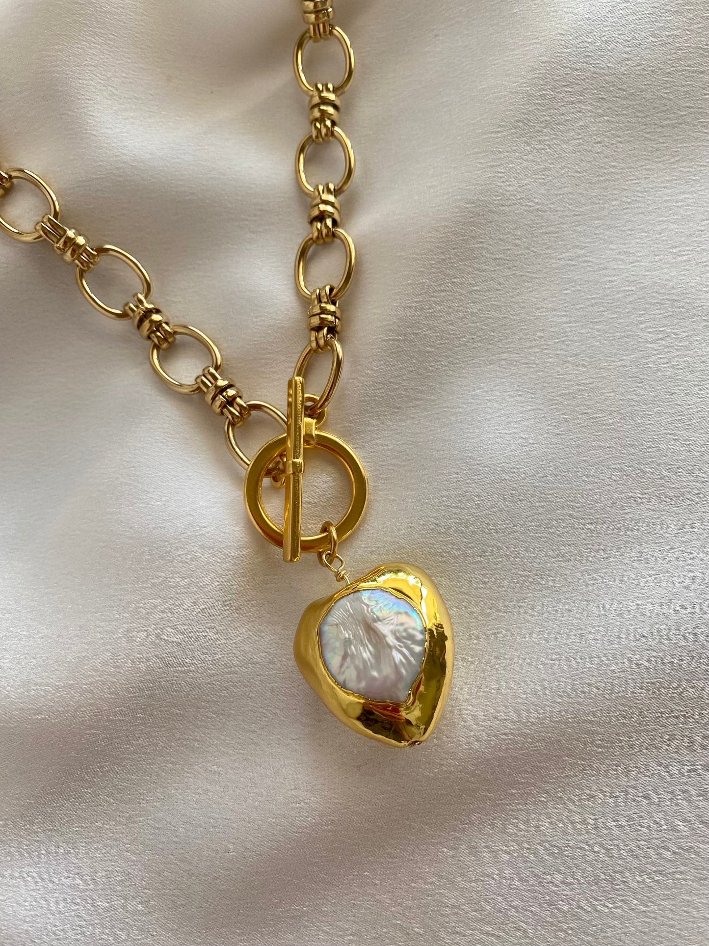Close-up of MONICA necklace showing heart charm and 18k gold plated chain