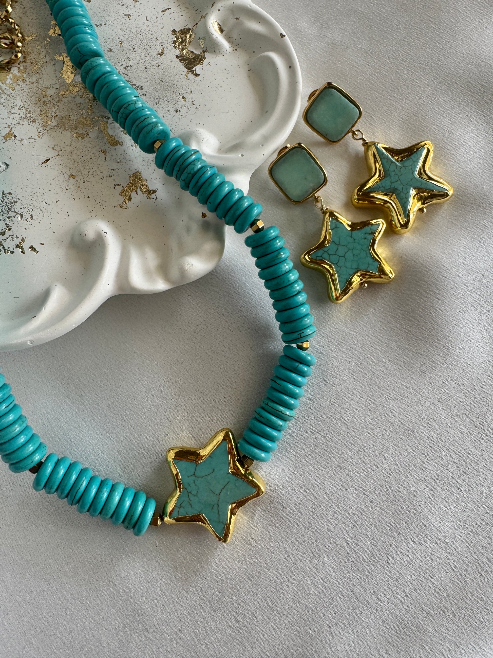 Handmade turquoise necklace and earrings with gold starfish charm by LOTUS by M on a white marble surface