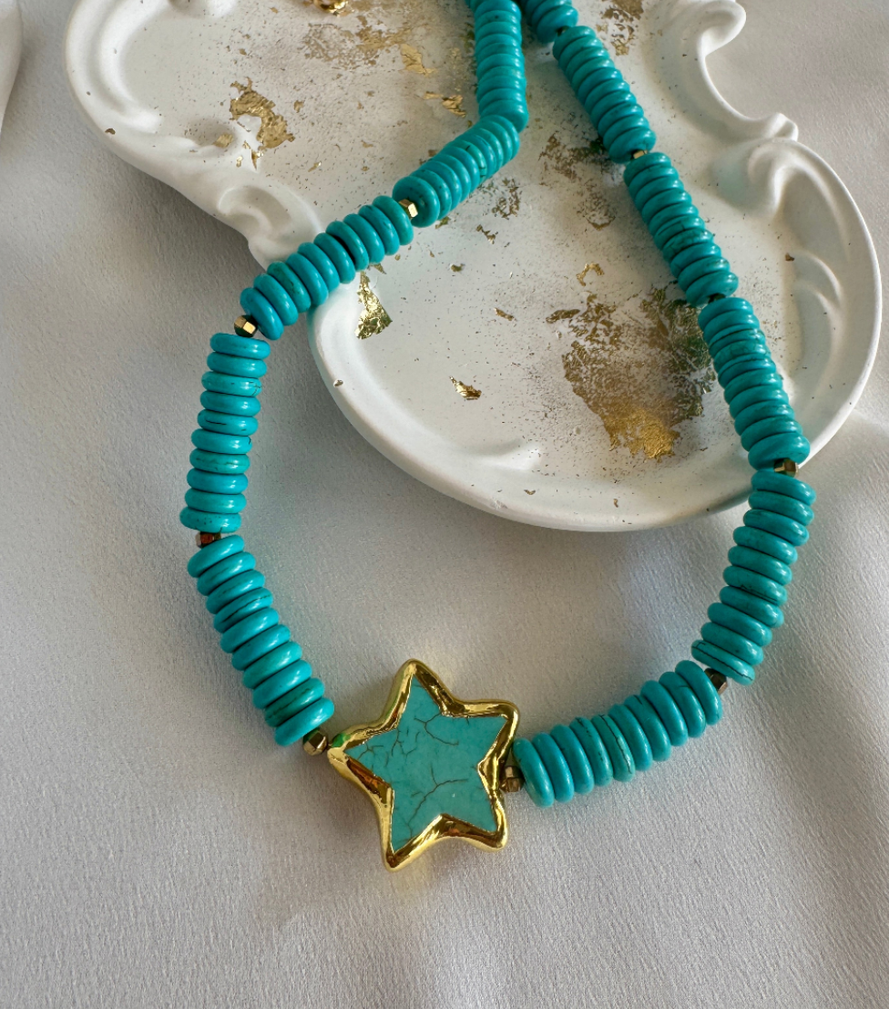 Turquoise beaded necklace with a star-shaped pendant on a light background