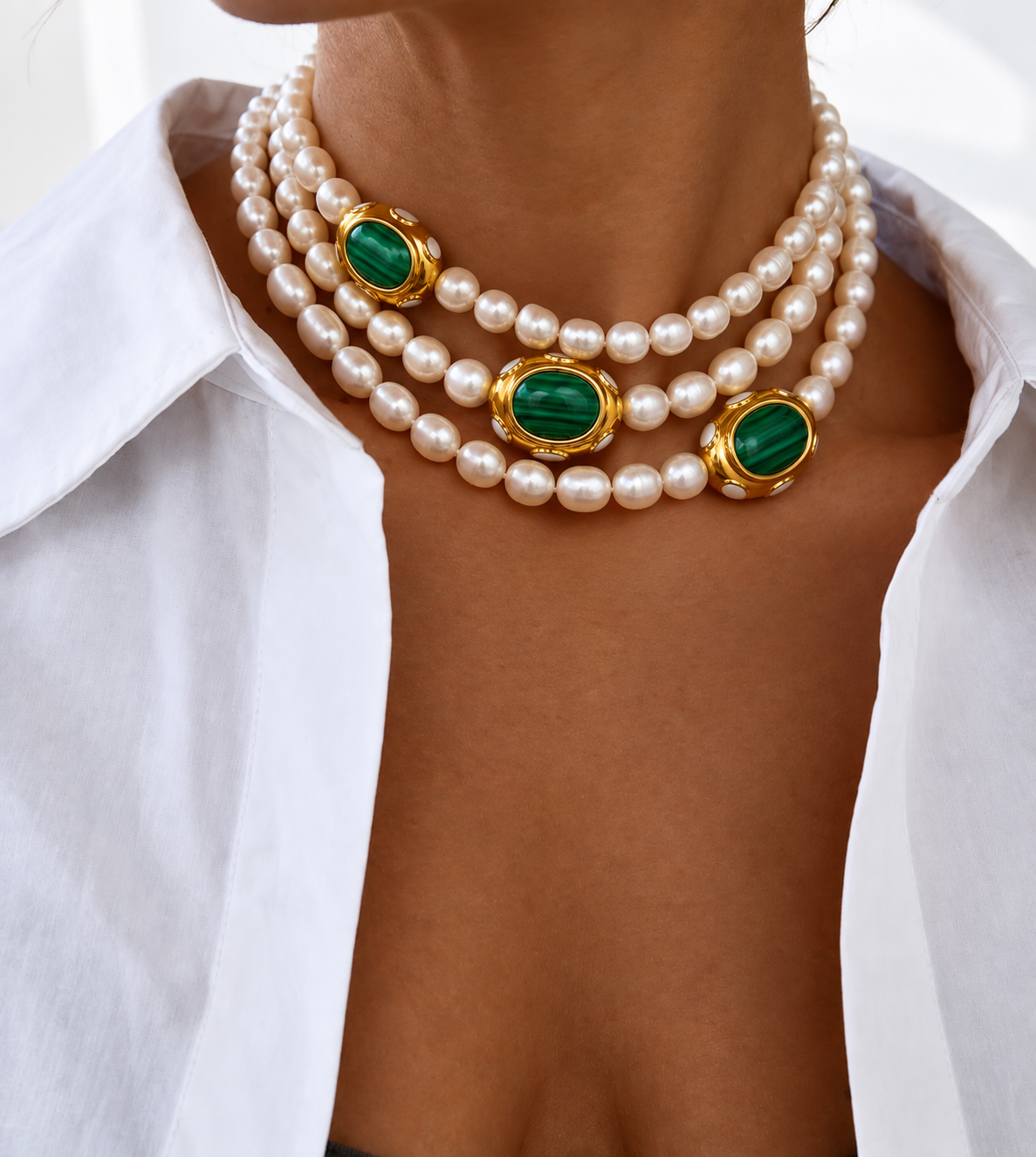 AIGLI pearl and green malachite necklace worn on neckline 3 times, styled with a white collared shirt.