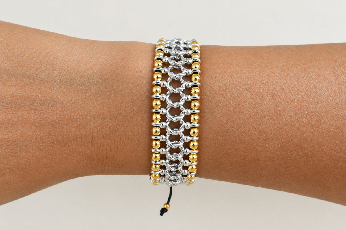Braid silver and gold bracelet on a wrist against a neutral background