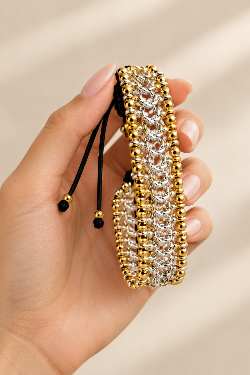 a beaded bracelet with gold and silver beads against a beige background