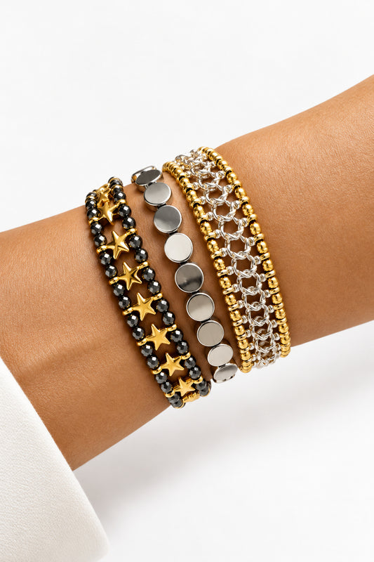 Close-up of a wrist wearing multiple bracelets on a neutral background