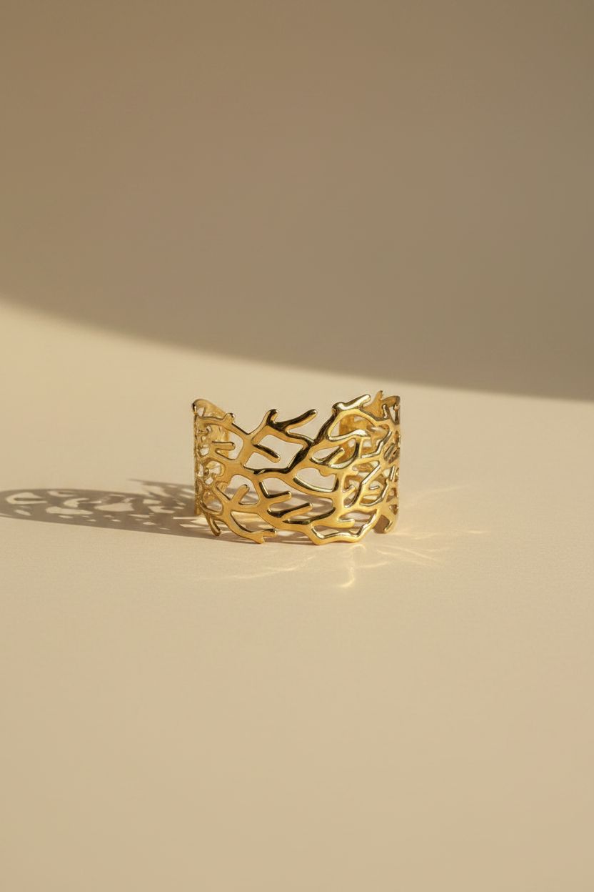 Gold bracelet with coral design on a beige background