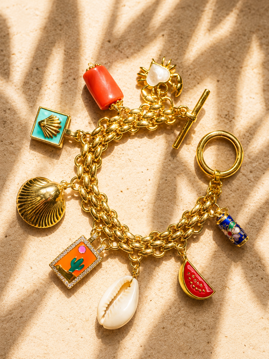 Gold charm bracelet with various summer charms on a beige background