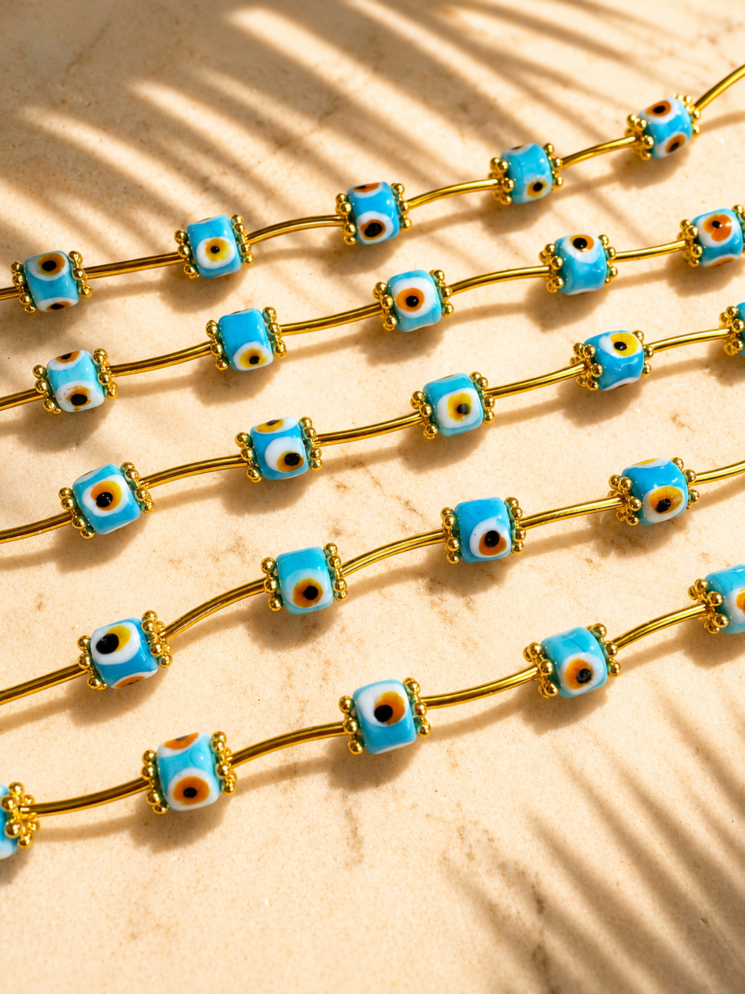 Bracelets with turquoise evil eye and gold elements on a beige background