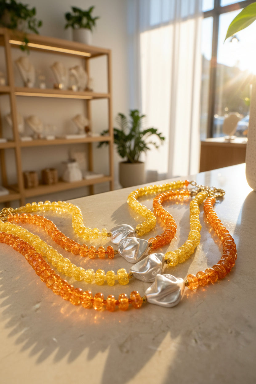 Necklace with orange and yellow beads and silver mother of pearl central bead on a marble surface in a shop