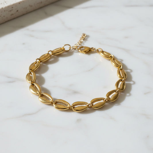 Gold shell bracelet on a textured stone surface