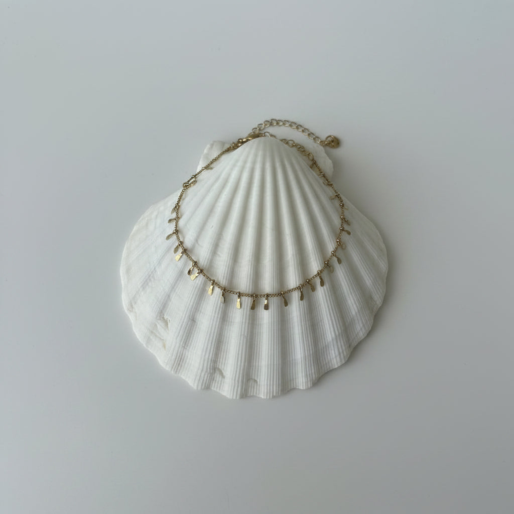 Gold anklet on a white shell