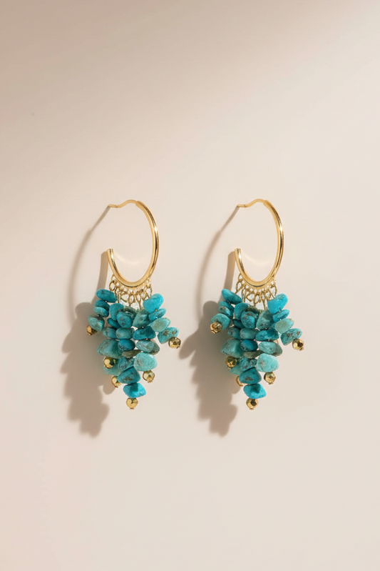 Turquoise earrings with gold hooks on a beige background