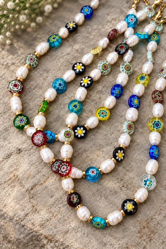 A colorful MILLEFIORI glass necklace with pearls, displayed on a neutral surface.